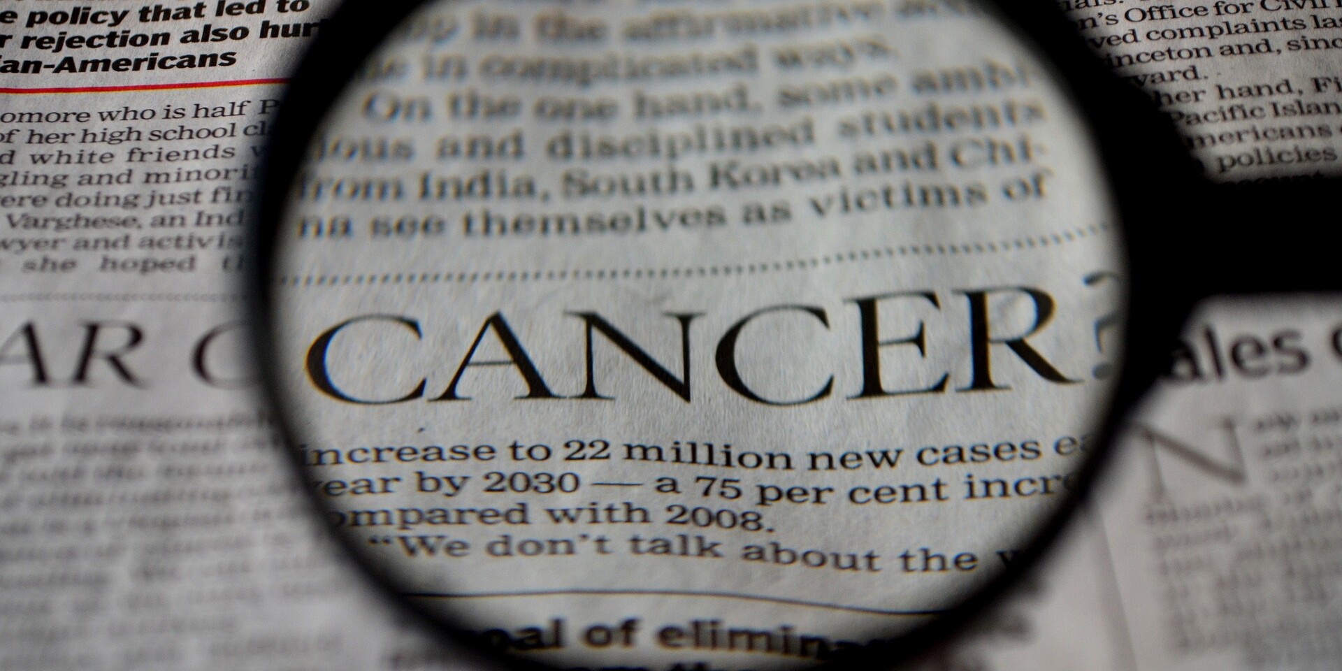 Das Bild zeigt einen englischen Zeitungsauschnitt bei dem das Wort Cancer mit einer Lupe vergrößert wird